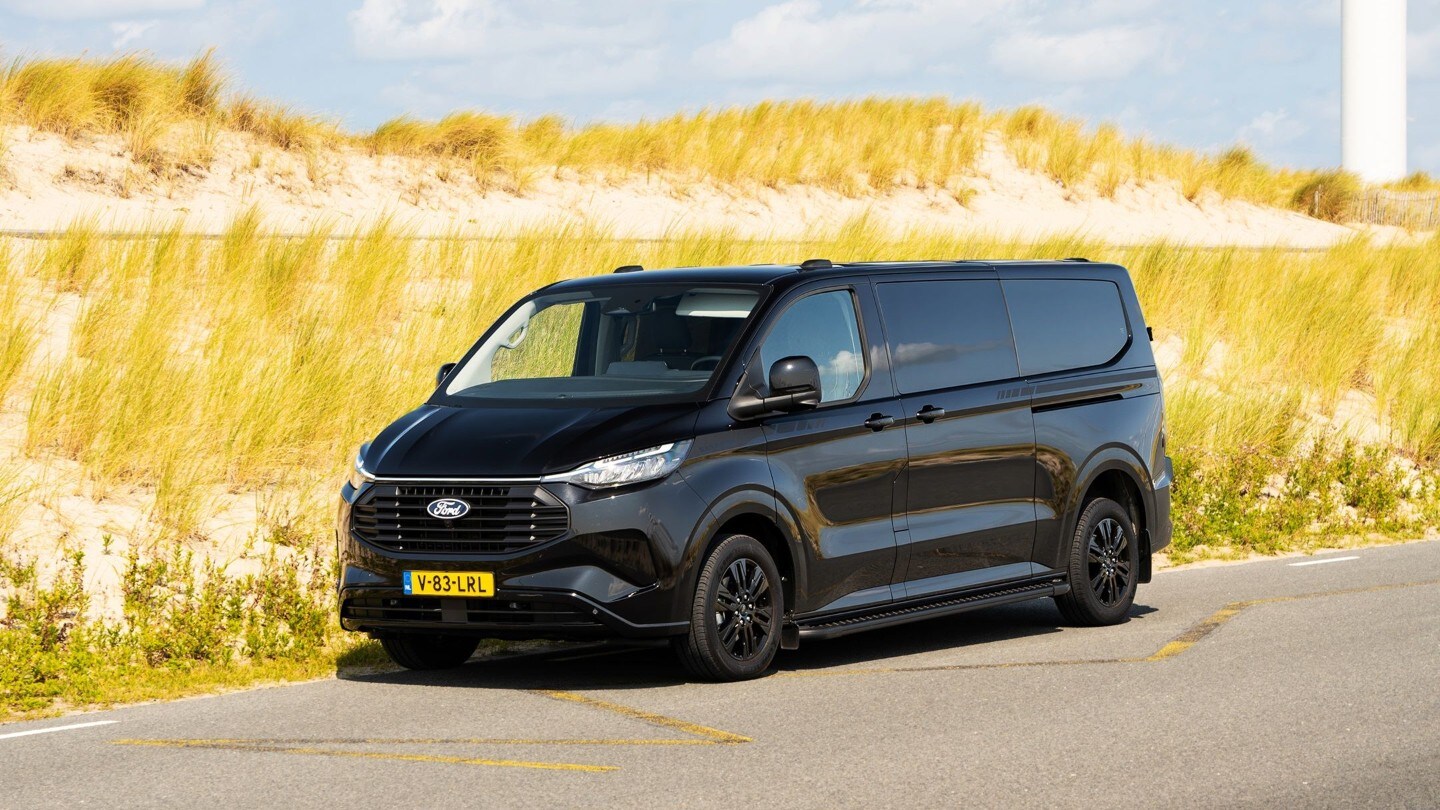 De zwarte Transit Custom PHEV Black Platinum rijdt op de weg, zijaanzicht.
