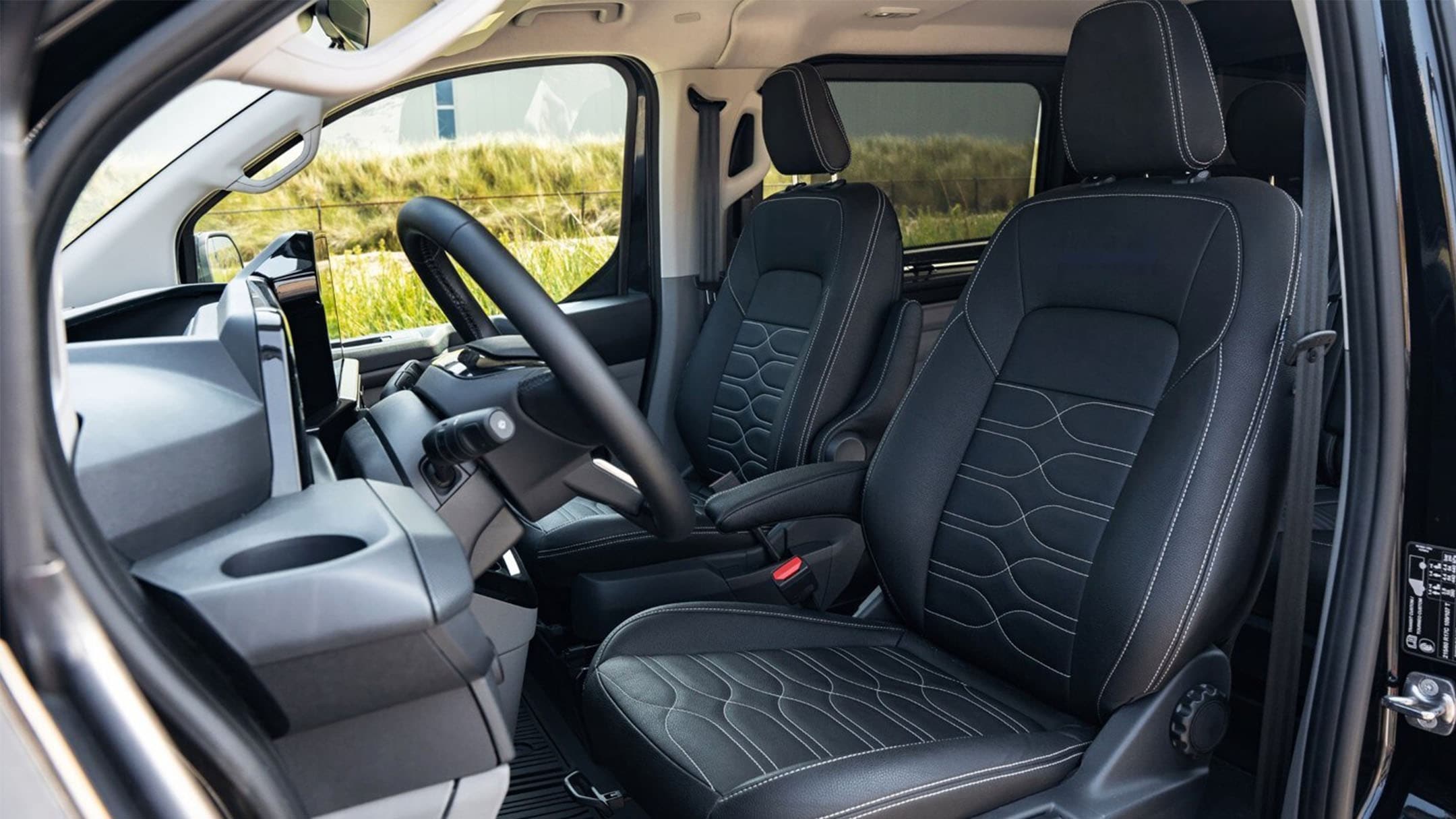Afbeelding van de binnenkant van de Ford Transit Custom PHEV Grey Platinum, waarbij de zwarte bekleding met grijze sticksels goed zichtbaar zijn.