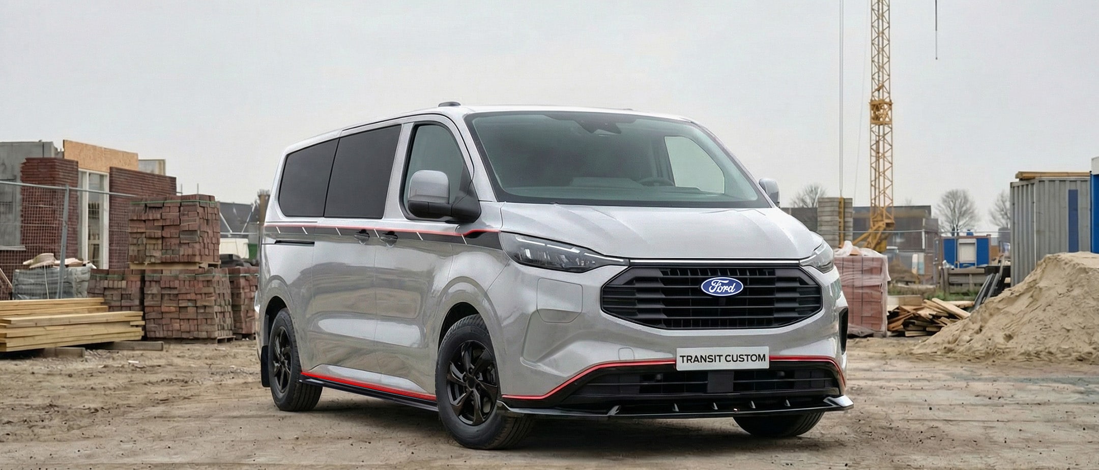 Vooraanzicht van de Ford Transit Custom PHEV Grey Platinum, en staat geparkeerd op een bouwterrein 