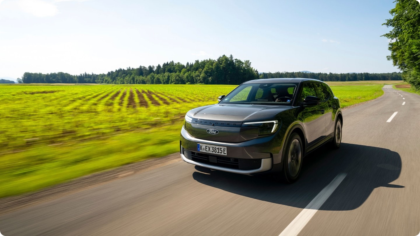 Brede opname van de volledig elektrische Ford Explorer (grijs) op de open weg.