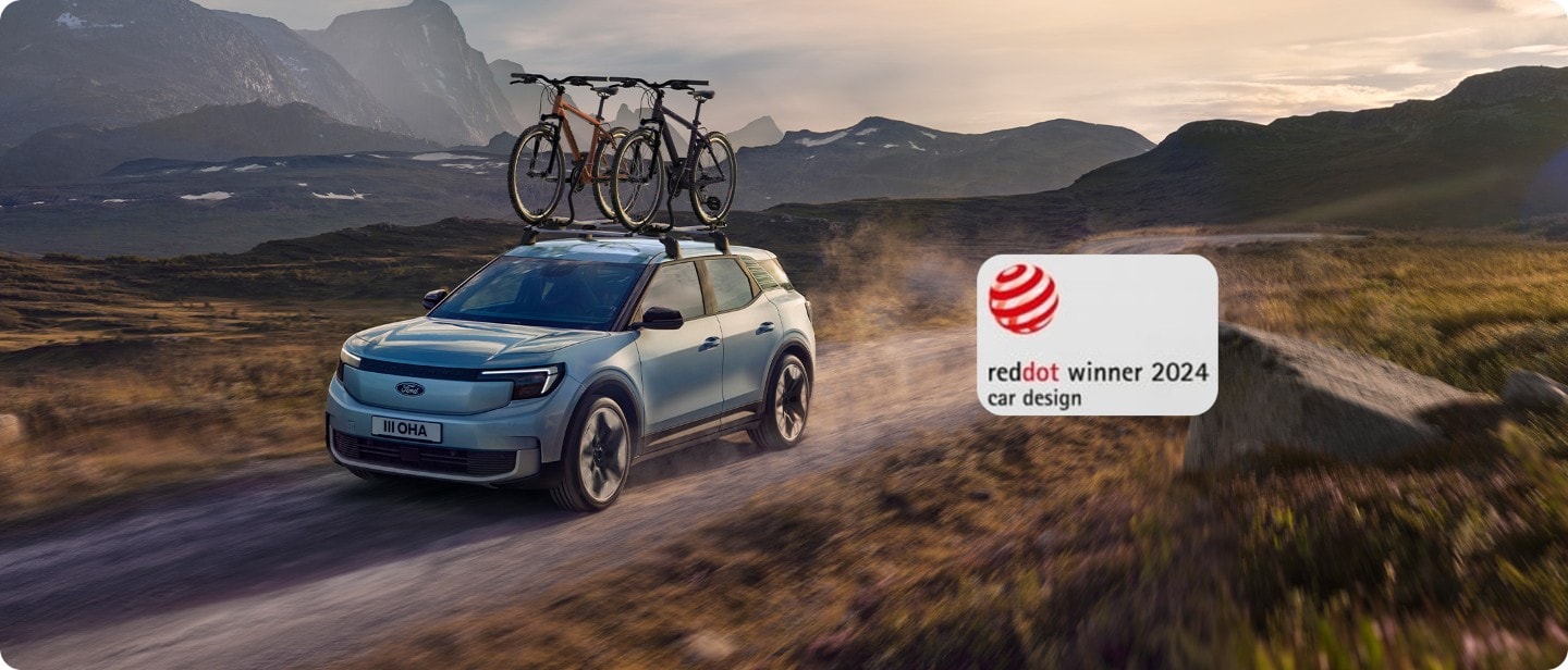 Brede opname van de volledig elektrische Ford Explorer (blauw) met fietsendrager op een open zandweg.