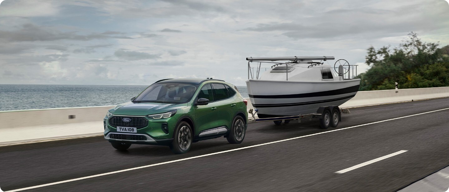 Brede opname van de Ford Kuga (groen) met boottrailer op de open weg.