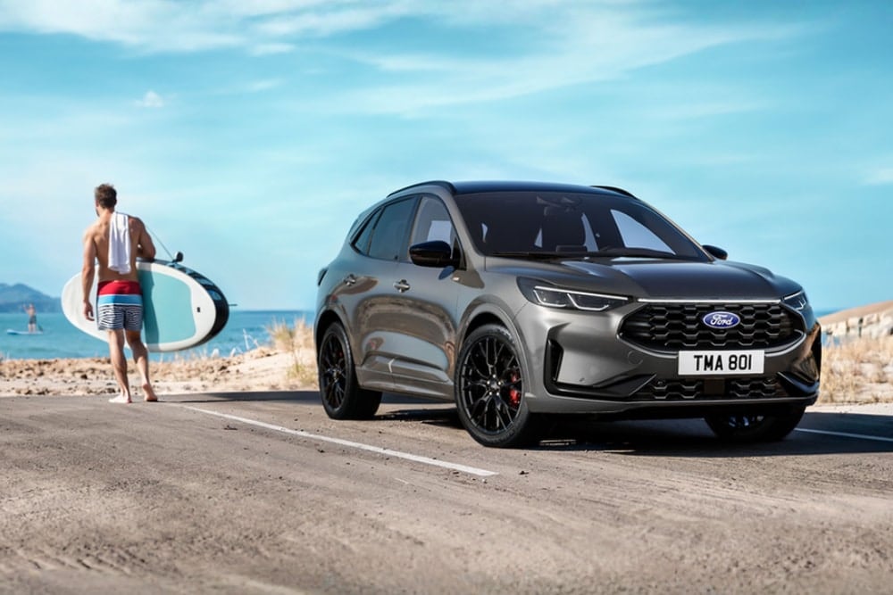 Surfer met surfboard loopt weg van zijn Ford Kuga