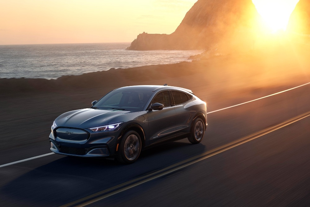 Ford Mach-E driving seaside road in sun set