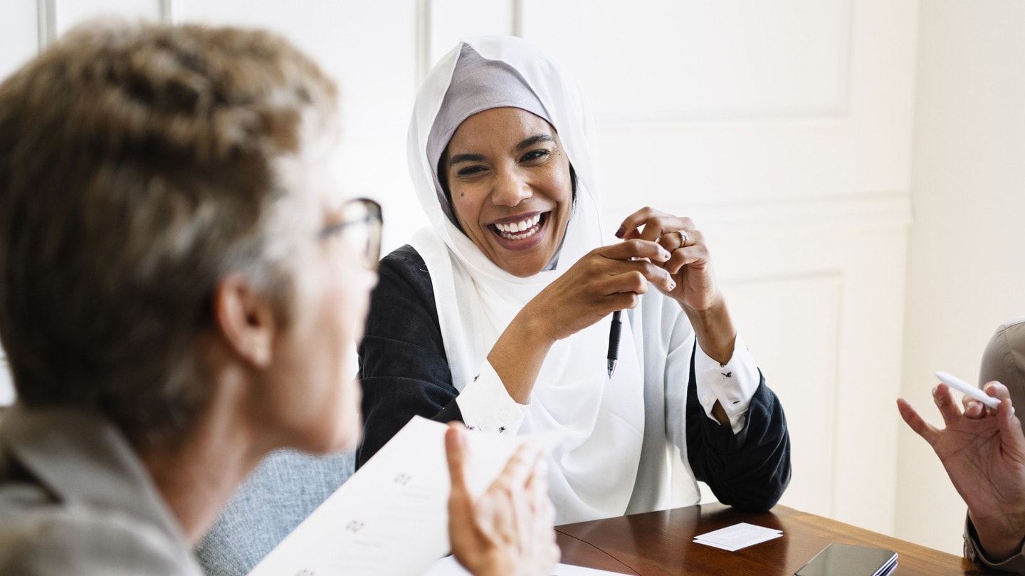 Three people sitting around a table and laughing