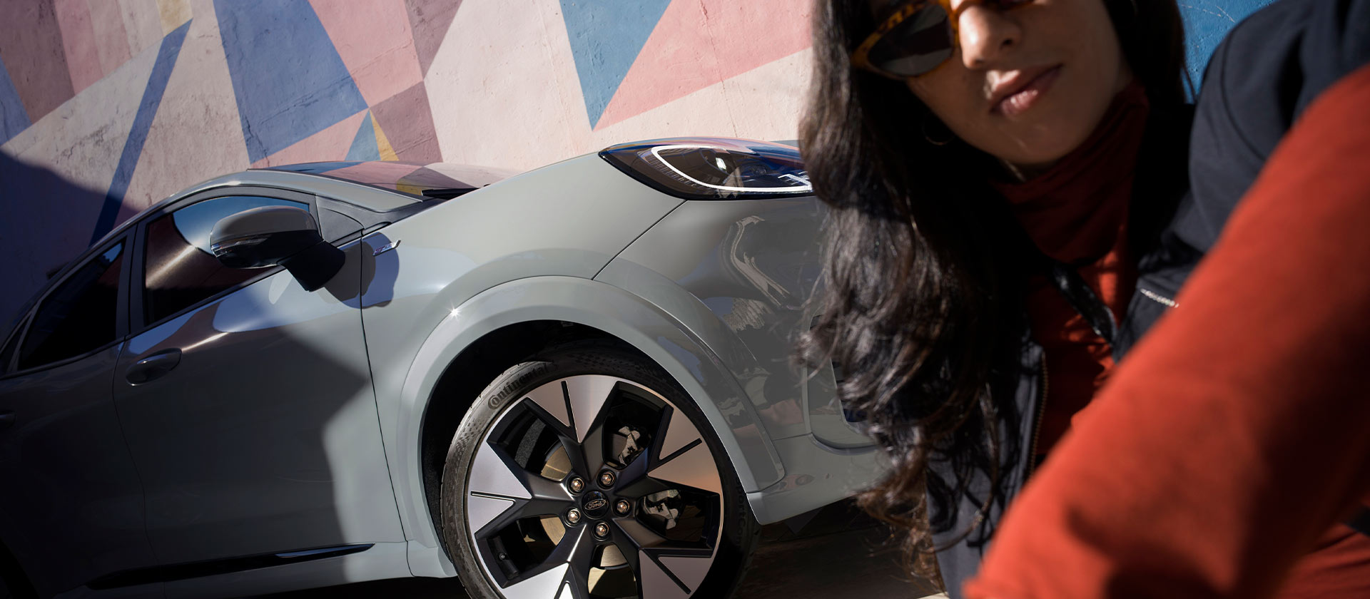 A person sitting next to a silver Ford Puma mild hybrid car. 