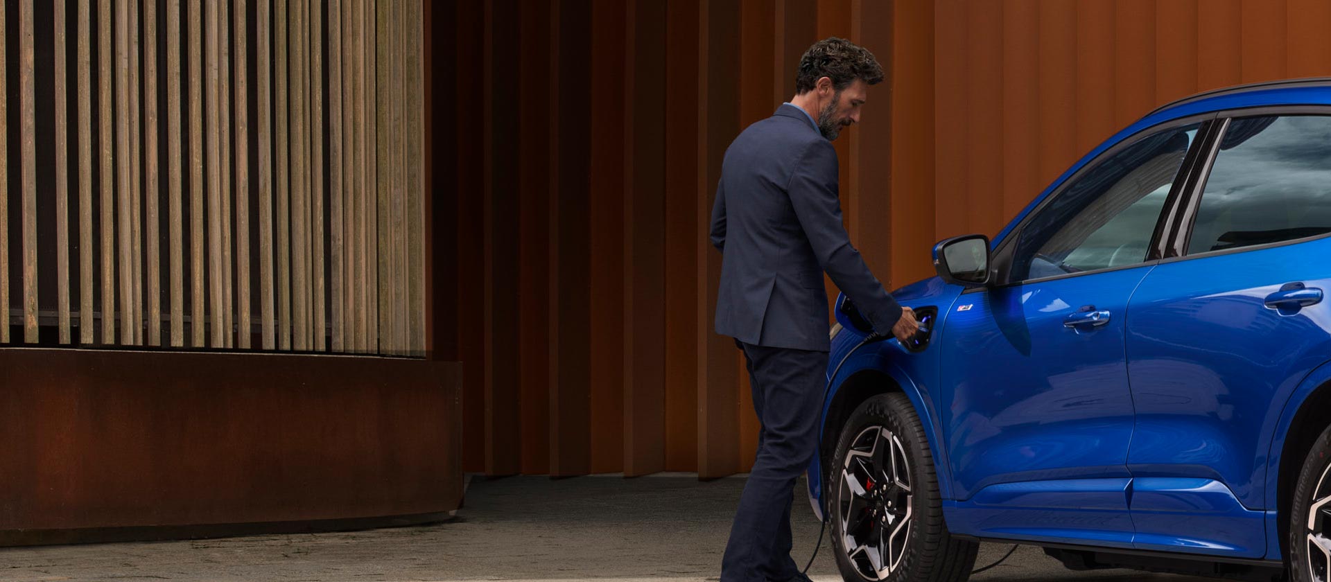 A person connecting a Ford plug-in hybrid car to an EV home charging cable.