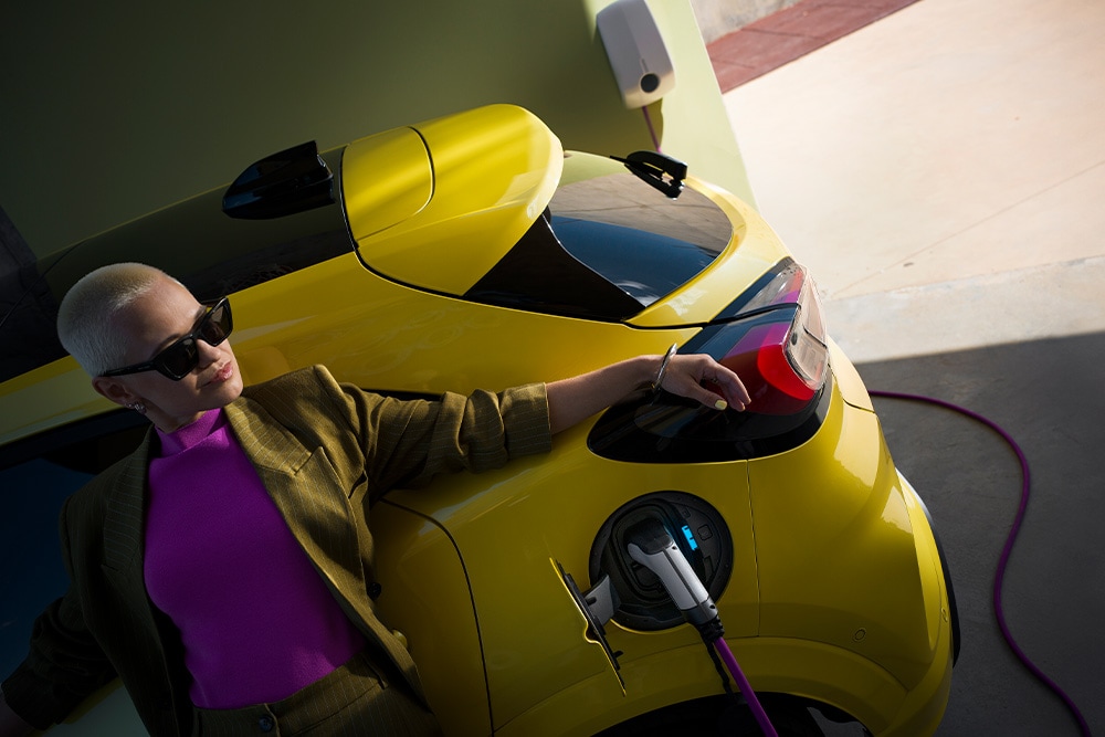 A person charging a yellow Ford Capri electric car. 