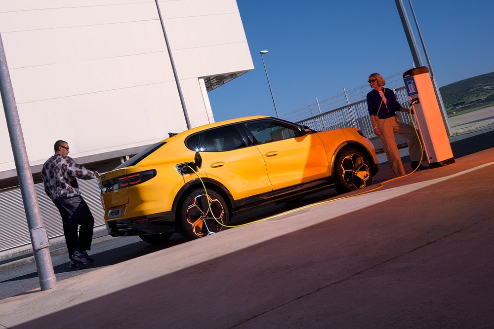 People charging a yellow Ford Capri EV at a public charging station. 