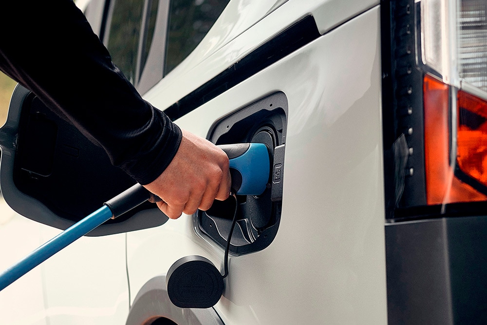 A person connecting a Ford electric vehicle to an EV charging cable.