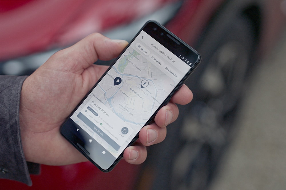 A smartphone displaying the FordPass™ app with nearby charging points for Ford EV public charging.