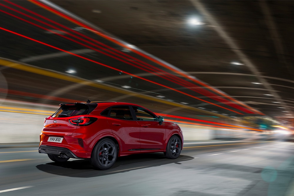 A red Ford Focus mild hybrid car driving through a tunnel. 