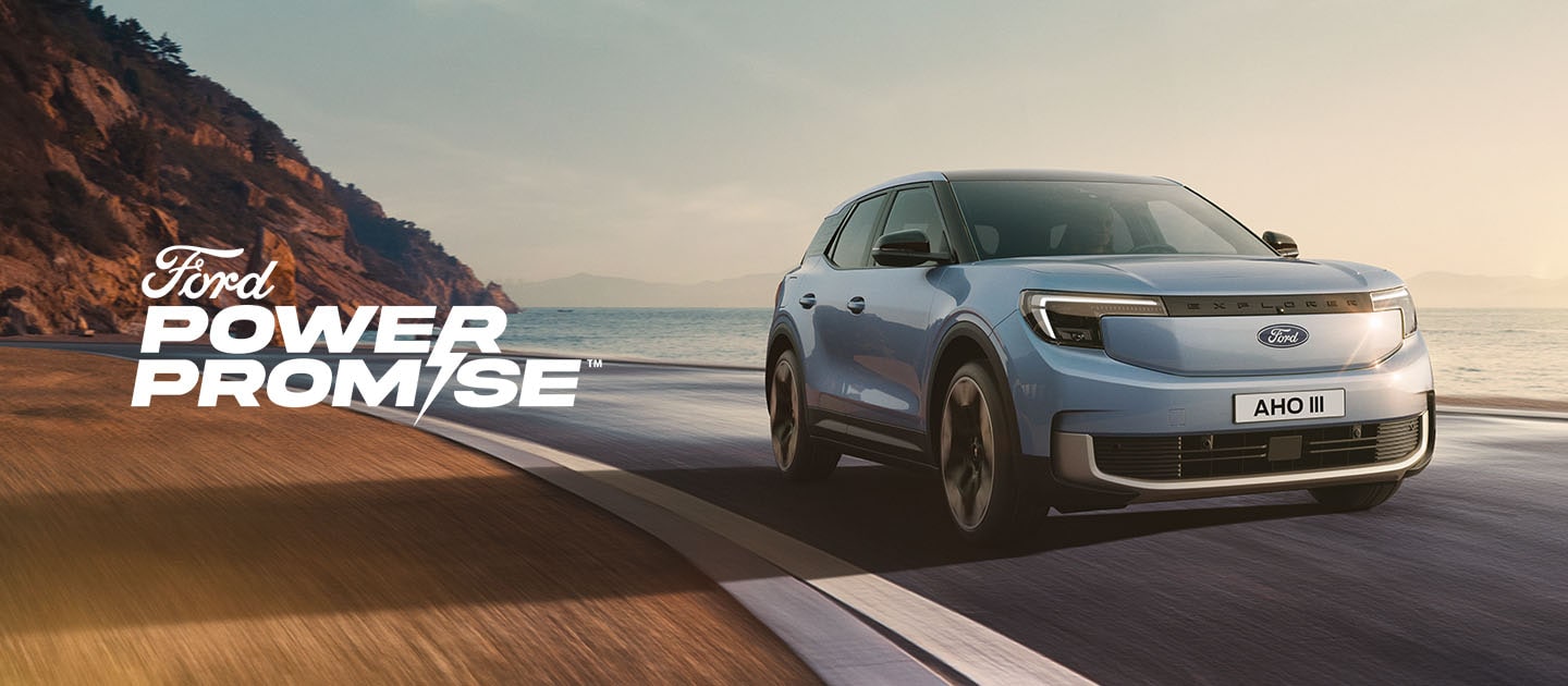 Een blauwe elektrische Ford Explorer rijdt over een kustweg in de schemering.