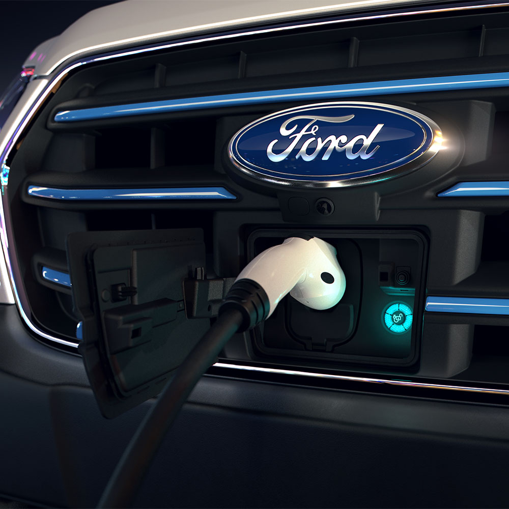 Close-up van een Ford E-Transit-laadpunt en de blauwe ovale Ford-badge op de grille.