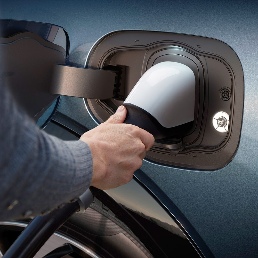 A person plugging an ultra-fast EV charger into a Ford electric vehicle. 