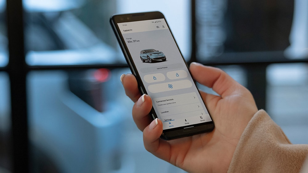 Een close-up van een hand die een smartphone vasthoudt en de FordPass-app gebruikt.
