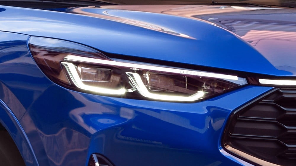 Een close-up van de koplamp van een blauwe Ford Mustang Mach-E.