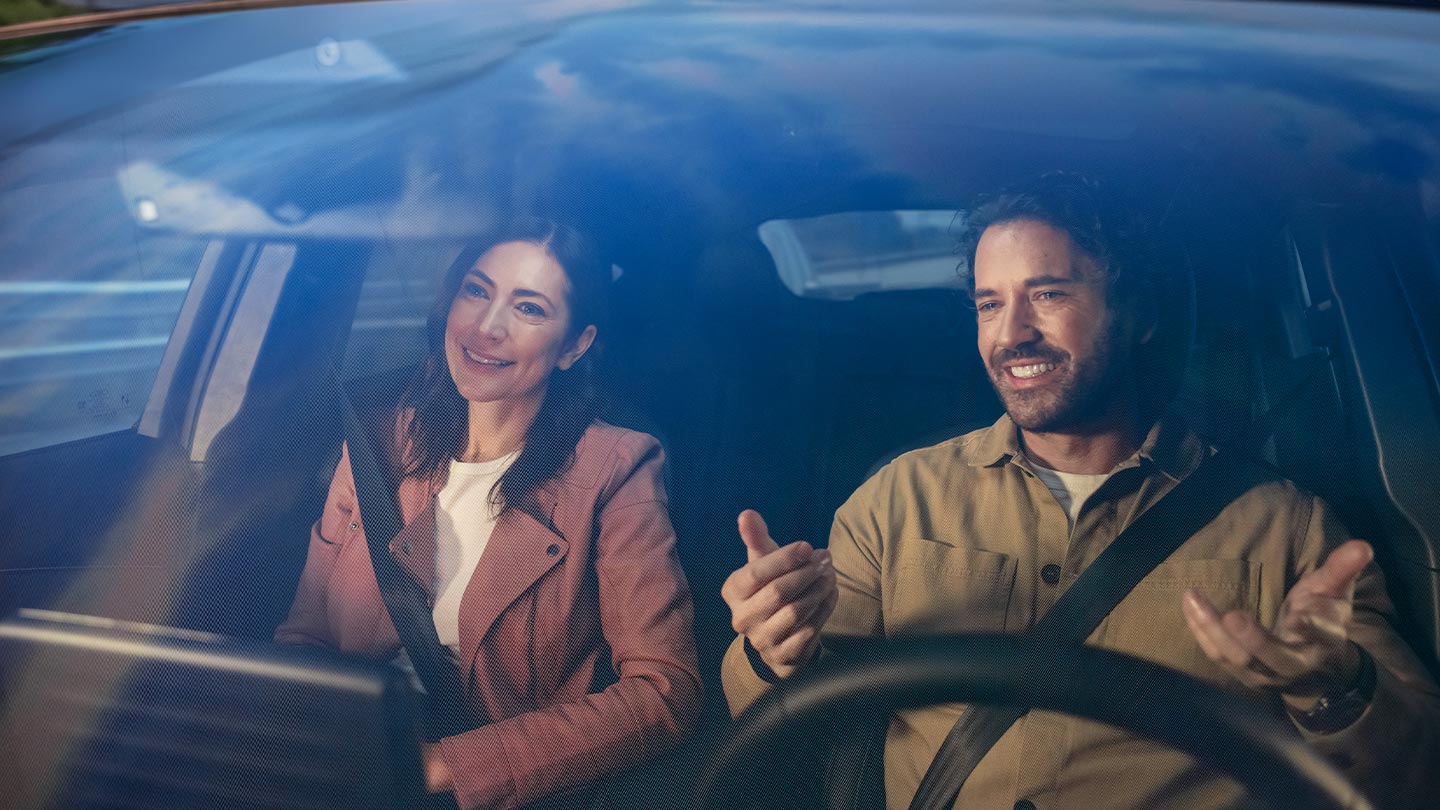 Twee mensen die op de voorstoelen van een Ford-voertuig zitten, beiden met veiligheidsgordels om.