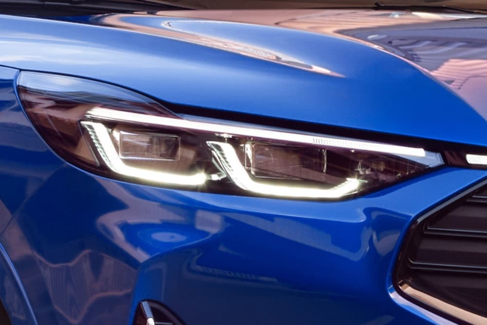 Een close-up van de koplamp van een blauwe Ford Mustang Mach-E.