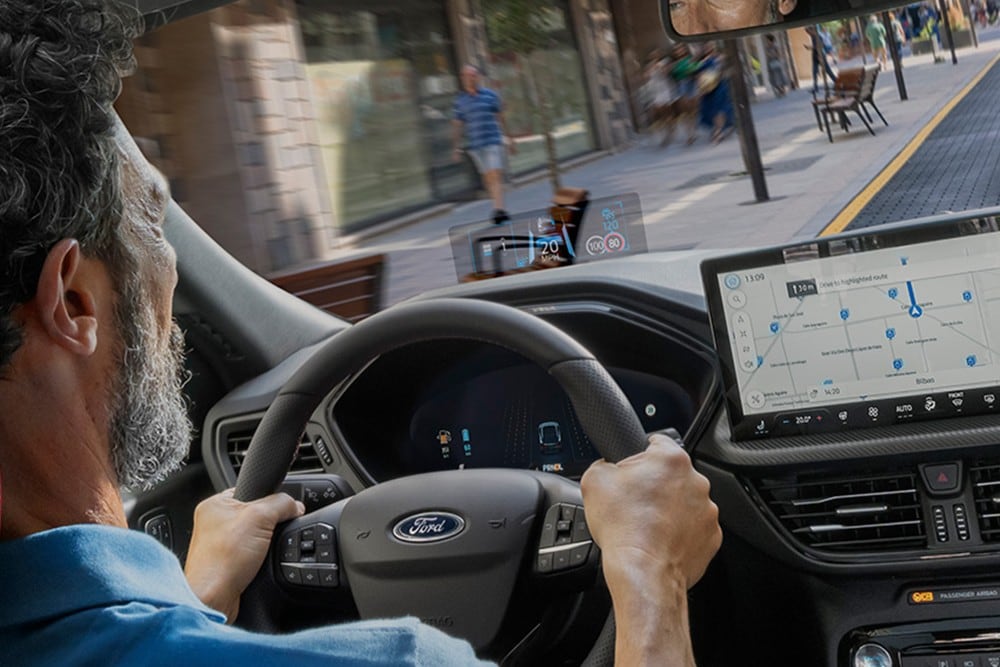 Een foto van een man die in een Ford Kuga door de stad rijdt, genomen vanuit de auto. 
