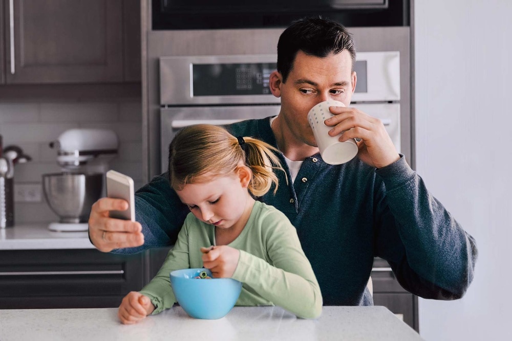 Man met kind die op zijn mobiele telefoon kijkt
