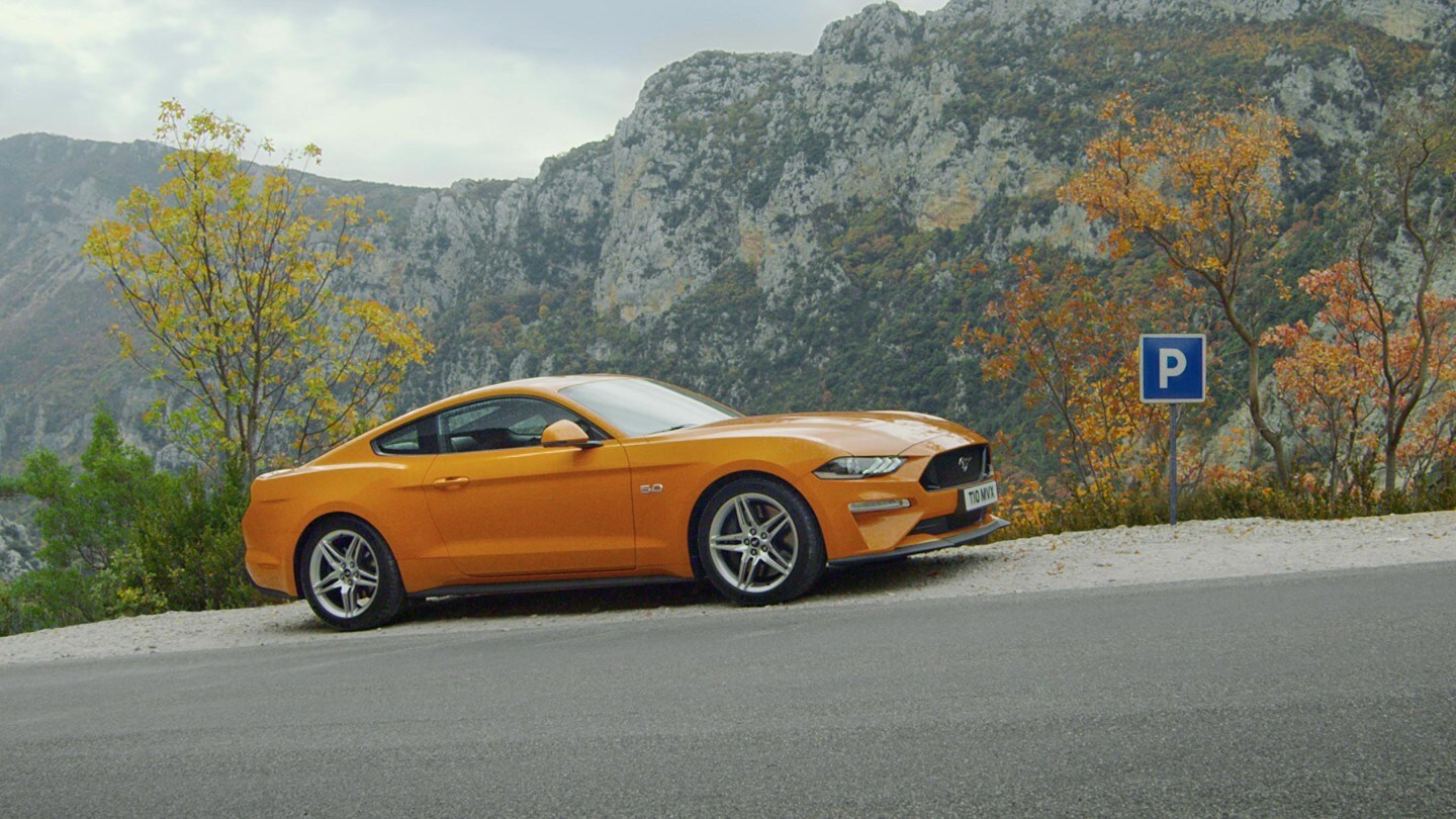 Oranje Mustang rijdt heuvel op