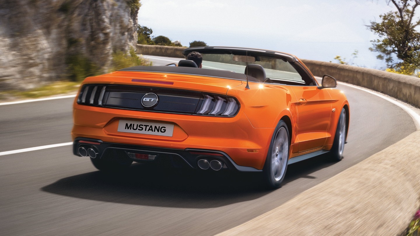 Oranje Mustang rijdt door de bergen