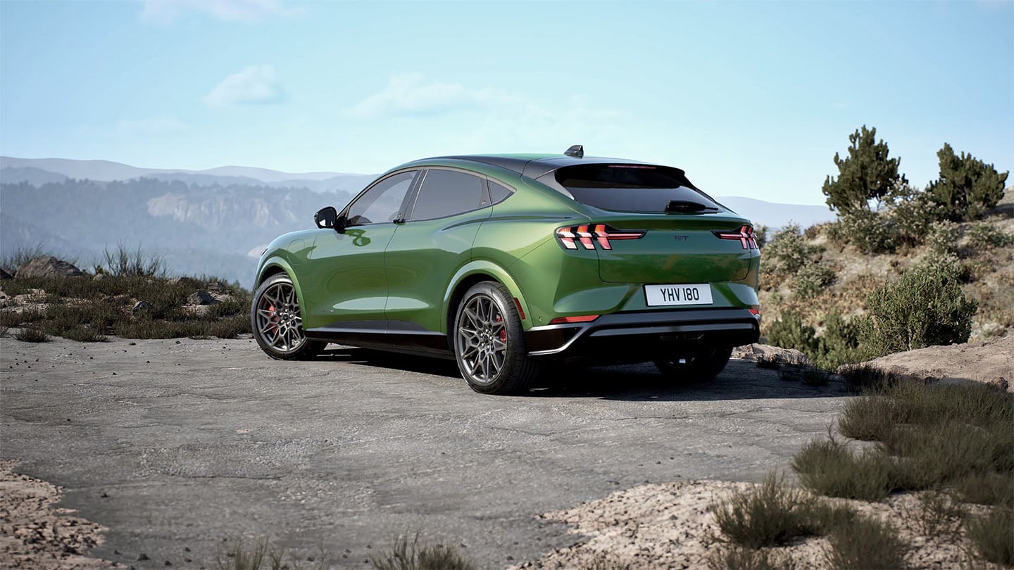 De achterkant van de Ford Mustang Mach-E GT in Eruption Green geparkeerd langs een bergweg.