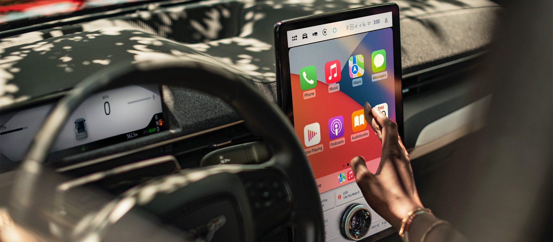Een close-up van de bestuurder van een Ford Mustang Mach-E die het grote 15,5" SYNC 4-touchscreen met Apple CarPlay gebruikt. 