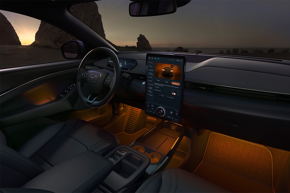 Het interieur van de Ford Mustang Mach-E 's nachts, met het 15,5" SYNC 4-touchscreen en oranje led-sfeerverlichting.