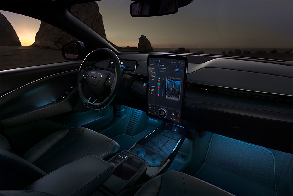 Het interieur van de Ford Mustang Mach-E 's nachts, met het 15,5" SYNC 4-touchscreen en blauwe led-sfeerverlichting.