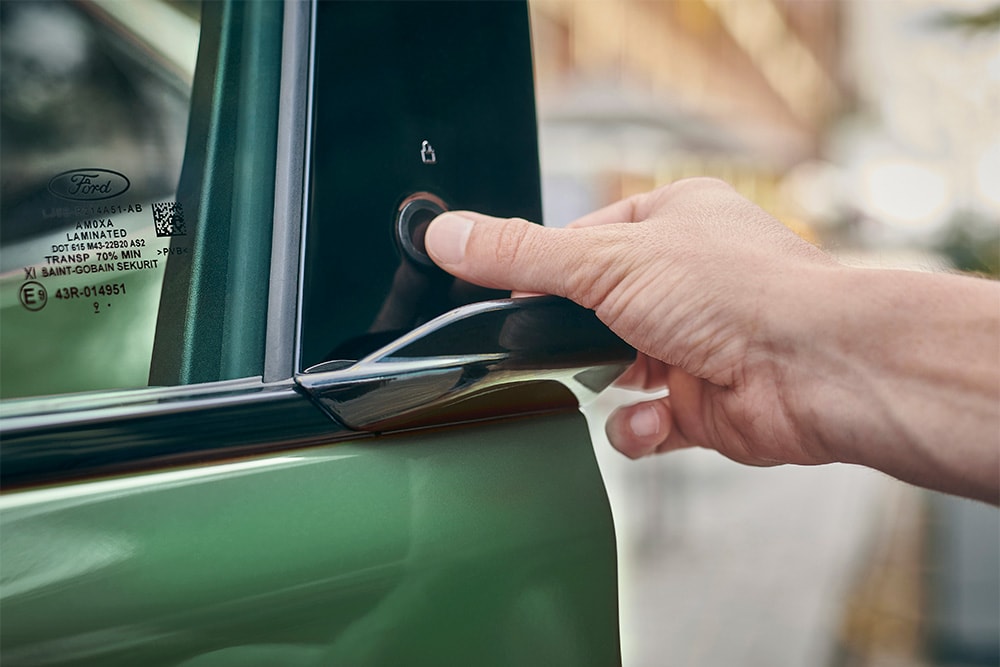 Een close-up van een hand die het E-Latch-systeem gebruikt door op een knop te drukken op de deur van een Ford Mustang Mach-E.
