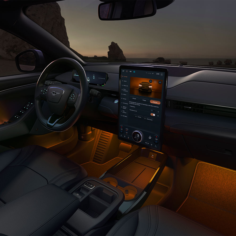Het interieur van de Ford Mustang Mach-E 's nachts, met het 15,5" SYNC 4-touchscreen en oranje led-sfeerverlichting.
