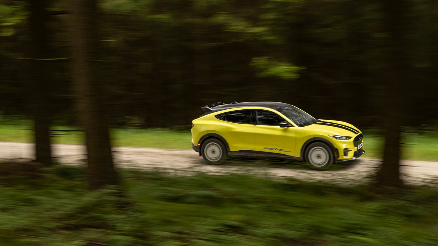 Mustang Mach-E Rally going through greenery on a dirt road