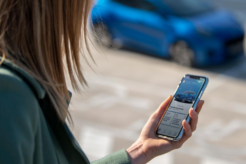 Vrouw staat voor haar Puma kijkt op FordPass via mobiel