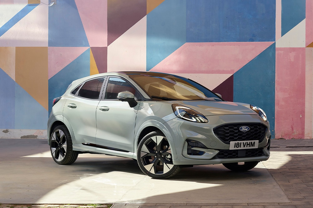 Zilveren Ford Puma SUV geparkeerd voor een kleurrijke, geometrische muurschildering.