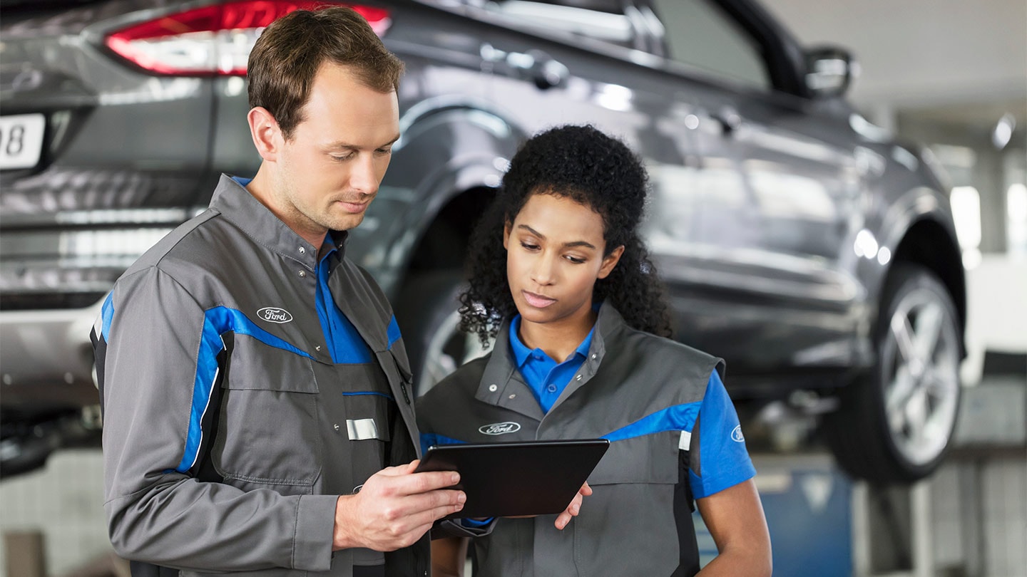 Twee Ford‑monteurs controleren op een smartphone het online serviceboekingssysteem.