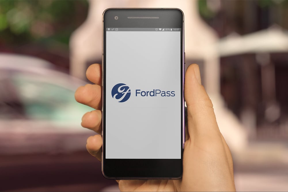 Hand met een mobiele telefoon waarop de Ford-app te zien is
