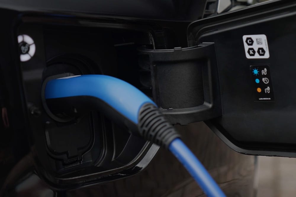 Close-up van een blauwe laadkabel, aangesloten op de laadpoort van een elektrische auto.