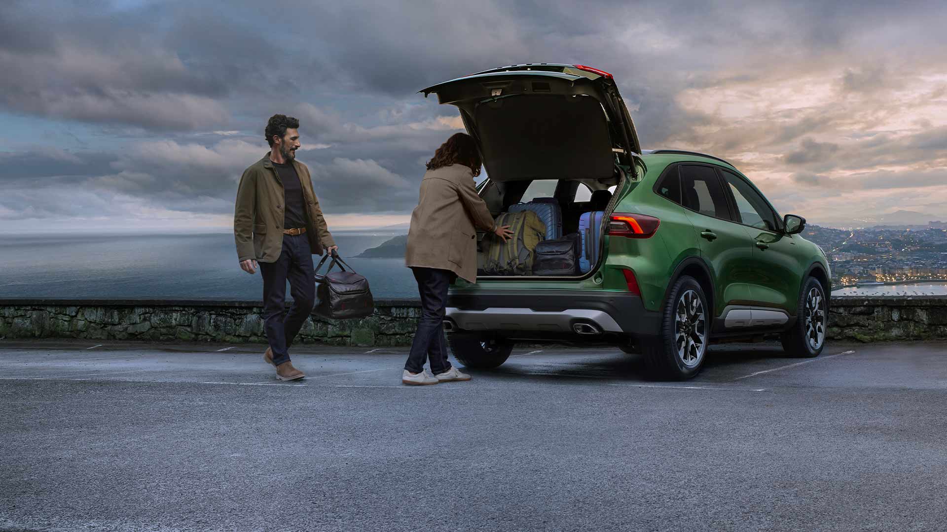 Twee personen laden meerdere koffers in de ruime kofferbak van de Ford Kuga.