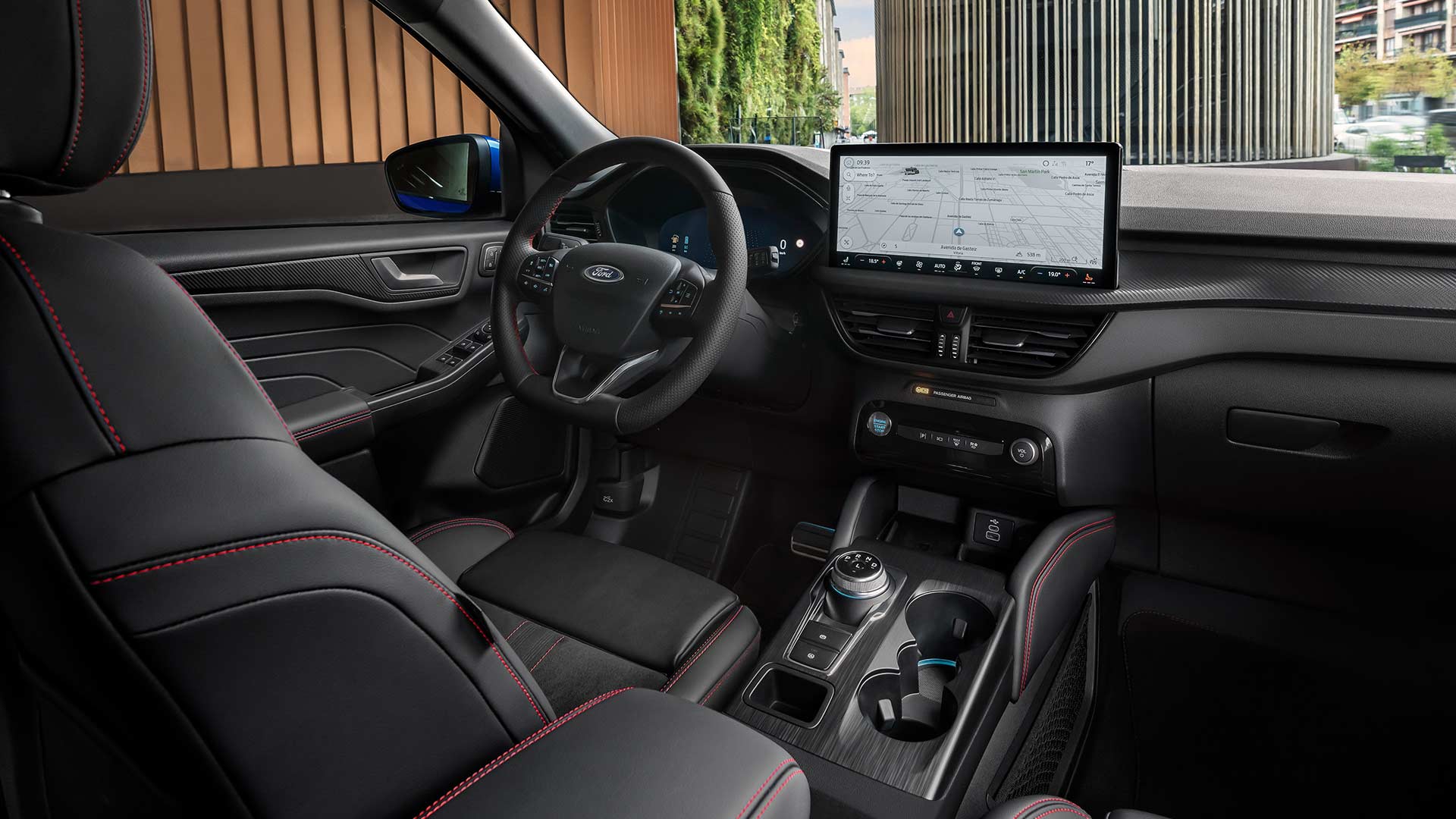 Interieur van de Ford Kuga met stuur met Ford-logo, groot SYNC® 4-touchscreen en zwarte stoelen met rode stiksels.
