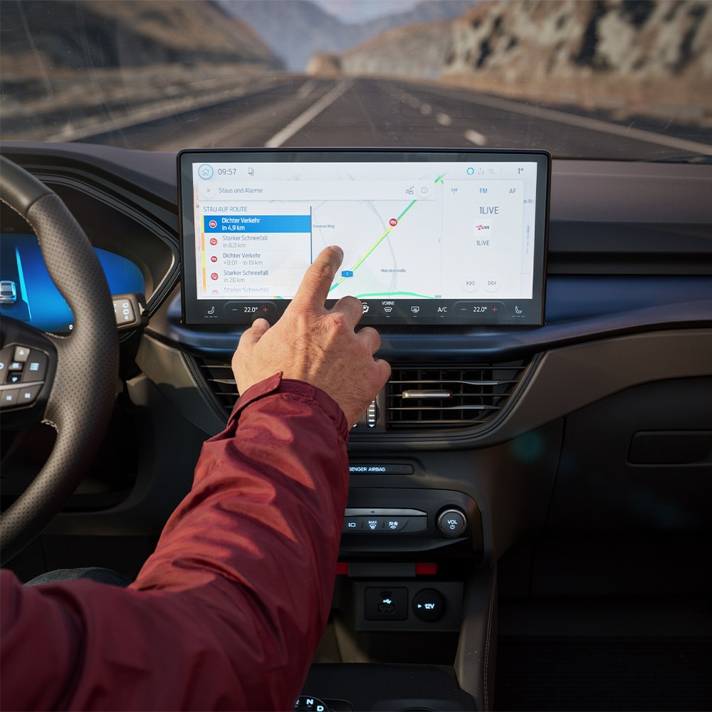 Een bestuurder gebruikt de Verbonden navigatie-functie op het digitale scherm van een Ford Kuga BlueCruise Edition.
