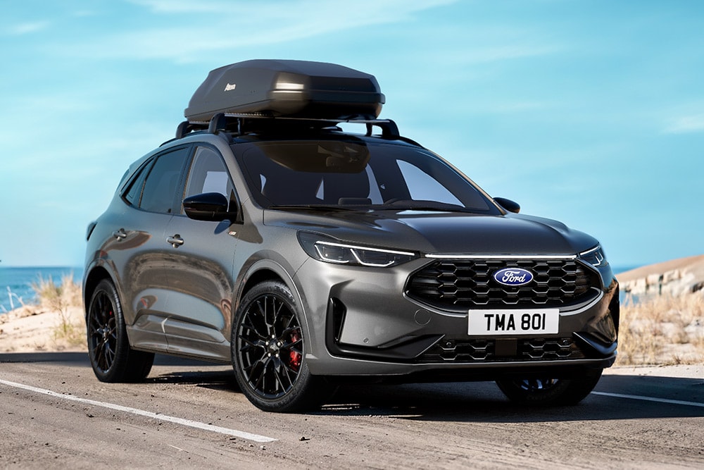 Een grijze Ford Kuga Black Package met een close-up van 20" zwarte lichtmetalen velgen en zwarte exterieurdetails met een dakkoffer