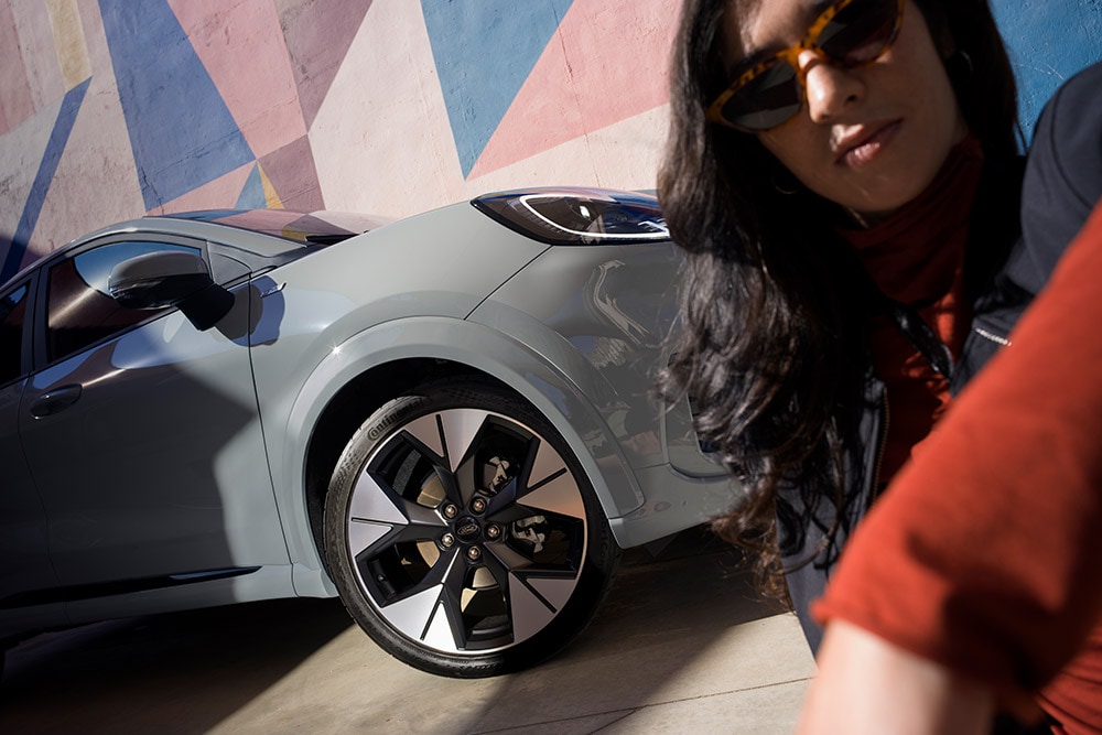 Een close-up van een persoon naast een grijze Ford Puma® met een EcoBoost®-benzinemotor.