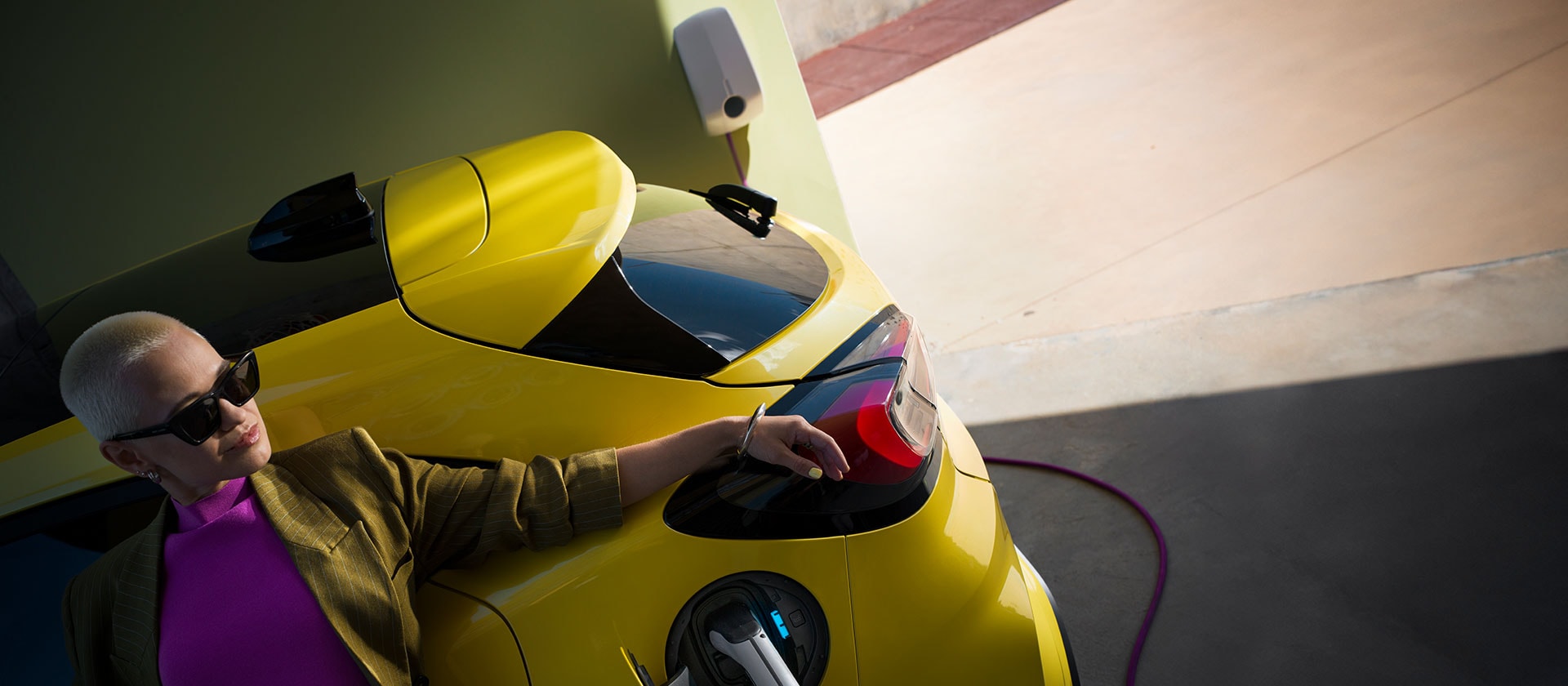 Een close-up van de achterkant van een gele elektrische Ford Puma Gen-E®, die thuis wordt opgeladen met een Wallbox.