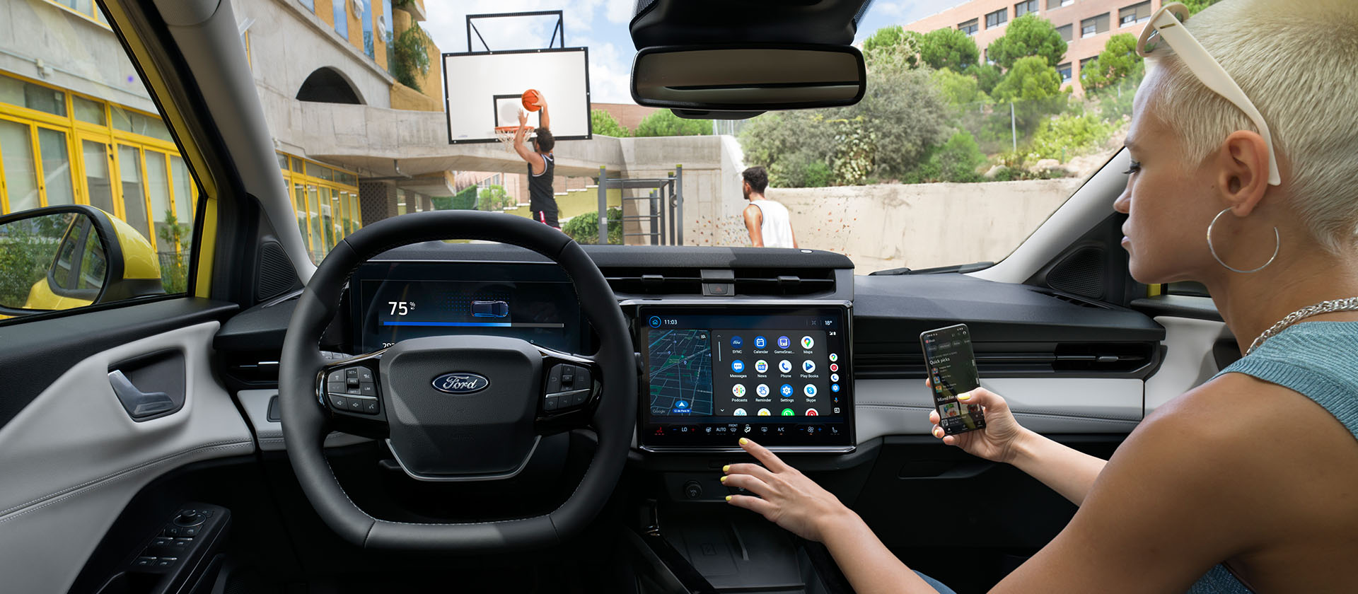Het interieur van de elektrische Ford Puma Gen-E®, terwijl iemand zijn mobiel draadloos synchroniseert met het touchscreen.