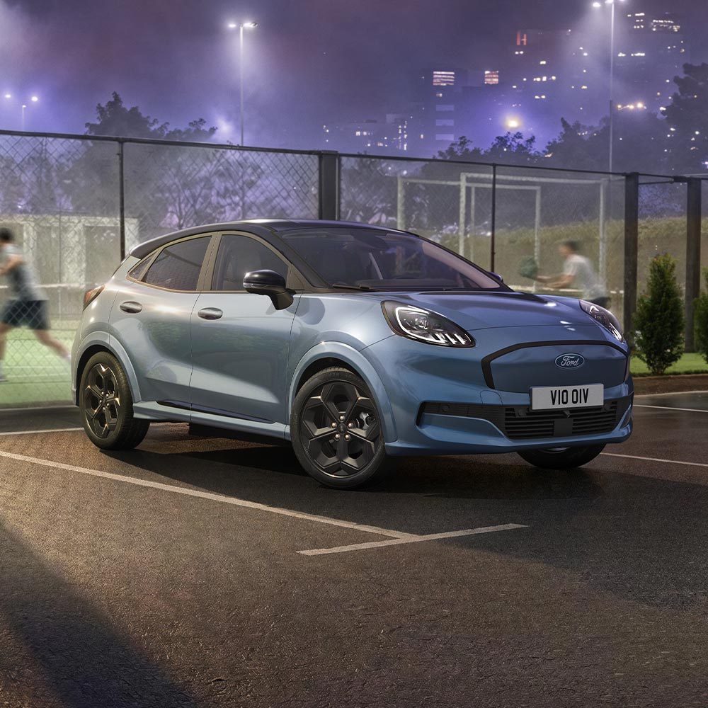 Een limited edition Vapour Blue Ford Puma Gen-E met BlueCruise-technologie staat geparkeerd naast een padelbuitenbaan.