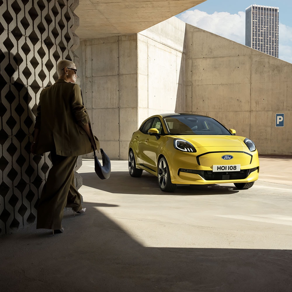 Een persoon loopt naar de nieuwe elektrische Ford Puma Gen-E®, in het geel.