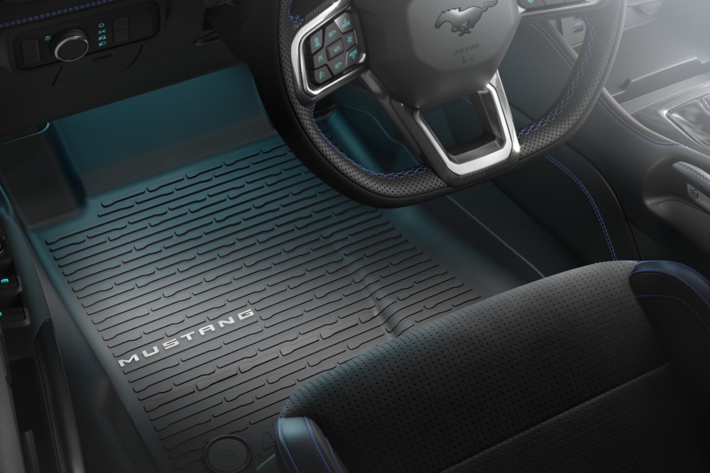 Interieurzicht van een Ford Mustang met het stuurwiel en een all-weather vloermat met de branding "MUSTANG".