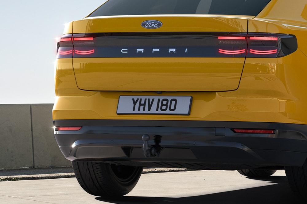 Achteraanzicht van een gele Ford Capri® die door de stad rijdt.